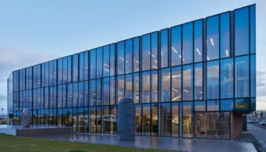 Un grand bâtiment en verre avec de nombreuses fenêtres et une statue devant lui.