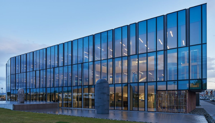 Un grand bâtiment en verre avec de nombreuses fenêtres et une statue devant lui.