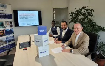 Signature de partenariat entre SOTI et Groupe PRISME pour optimiser la gestion des parcs mobiles, avec trois hommes signant des documents dans une salle de réunion.