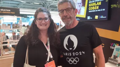 Yasmine Achour, rédactrice en chef de MedTech France, pose avec Michel Cymes lors du salon Viva Technology à Paris. Elle participe à un événement dédié aux innovations technologiques, avec en arrière-plan une affiche pour une séance de dédicaces avec l'auteur Harlan Coben.